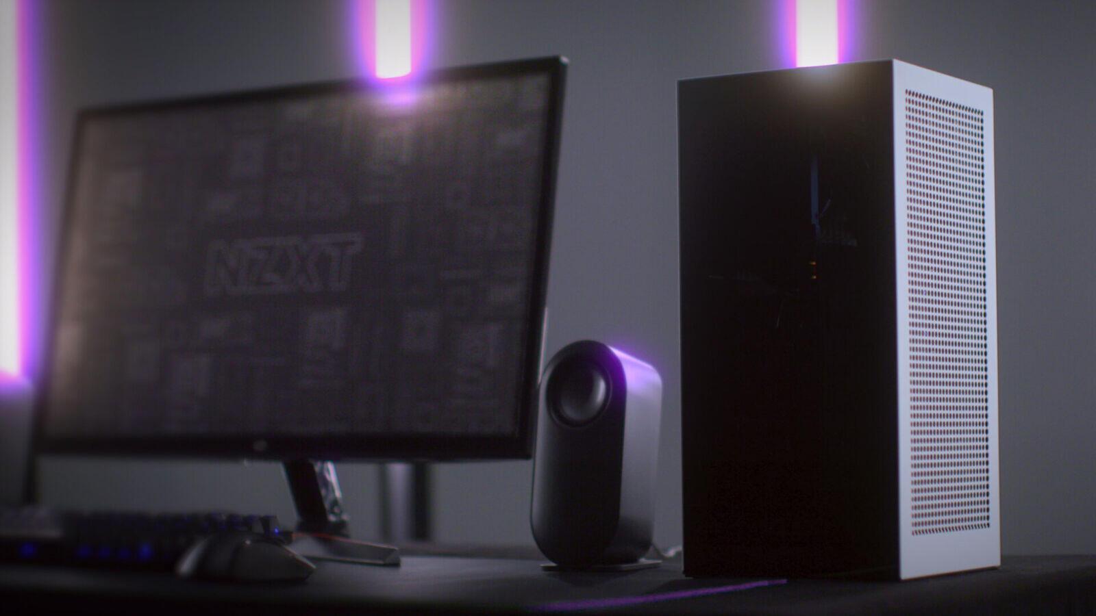 NZXT H1 V2 small form factor PC case on a desk beside a monitor and speaker, official lifestyle product photo from NZXT's H1 V2 launch announcement